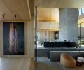 The home’s massive anchor point – the two-sided fireplace with hand troweled plaster by Euro Plastering, counters Michael Brophy’s snag tree painting at the dining room entrance. Left, a terrace for entertaining with hot tub. Ceilings and floors are wrapped in Oregon white oak by Castle Bespoke.