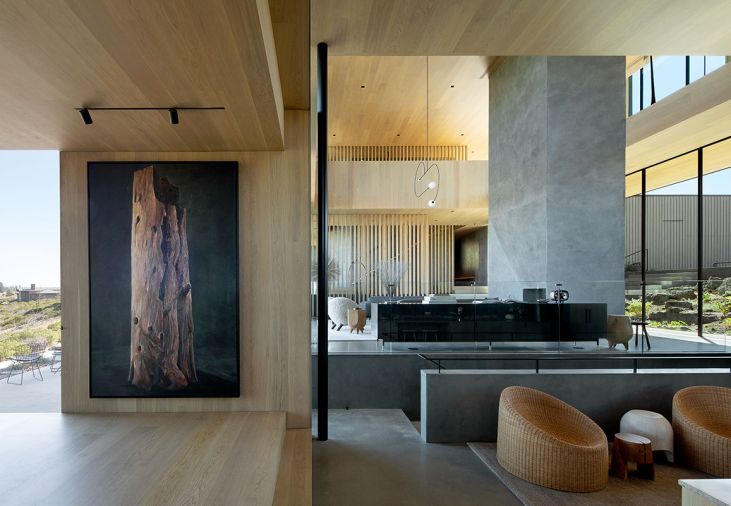 The home’s massive anchor point – the two-sided fireplace with hand troweled plaster by Euro Plastering, counters Michael Brophy’s snag tree painting at the dining room entrance. Left, a terrace for entertaining with hot tub. Ceilings and floors are wrapped in Oregon white oak by Castle Bespoke.