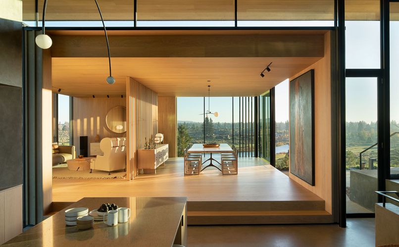 Looking from the kitchen, the dining room features a Slab Wishbone custom table and square BDDW chairs. A wood-slatted screen separates the sitting room.