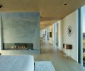 The primary suite can be closed off for privacy by a large (unseen) pivot door. The central fireplace rises into the suite with a silvery plasterwork finish. Artworks adorning the walkway to guest bedrooms include Louise Nevelson and Richard Serra. Slab bed by BDDW.