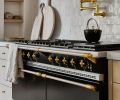 A Lacanche range is topped with a brass pot filler and a backsplash of Zellige, Idris by Ait Manos tile from Ann Sacks.