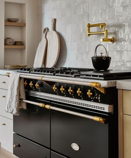 A Lacanche range is topped with a brass pot filler and a backsplash of Zellige, Idris by Ait Manos tile from Ann Sacks.