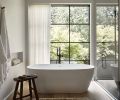 The primary bathroom beacons with a Kohler Purist tub filler accenting the Ocala tub and calming views. The airy window coverings are from Lesley Petty Workroom.