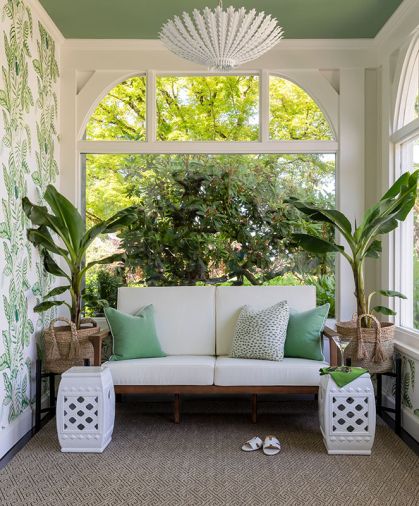 The wallpaper is the Sanderson Calathea Botanical Green from Kelly Forslund. Vintage ceramic side tables and plants nestled in handwoven baskets frame the love seat.