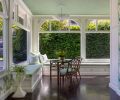Custom window seats in the sunroom were designed by Nifelle Design and built by Northwest Heritage Renovations, with a vintage bamboo rattan Brown Jordan table and chairs, and Hampton Large Chandelier from Visual Comfort.