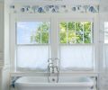 The Alexa Hampton Markos light in polished nickel was installed above the soaking tub and Carrera White Marble floor.