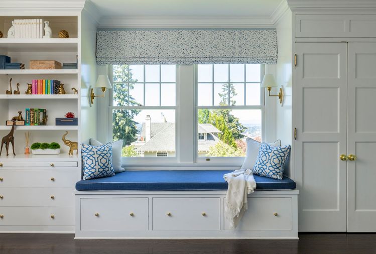 The existing cabinetry and window seat were perked up with thoughtful touches. A custom roman shade in Schumacher Skittles “Blueberry/Sky”, custom pillows from Thibaut, and navy textured fabric upholstery from Kravet were added to create a comfy reading nook.