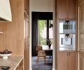 The intimate dining room tempts guests away from the bright kitchen with a moody color palette grounded in Kravet window coverings and the deep warm gray of the ‘Urbane Bronze’ plasterwork.