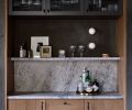 A favorite entertaining detail is the custom-built bar in the dining room. Reeded glass subtly conceals the glassware and bar tools in the upper cabinet. Allure Quartzite shelves and backsplash pull the look together.