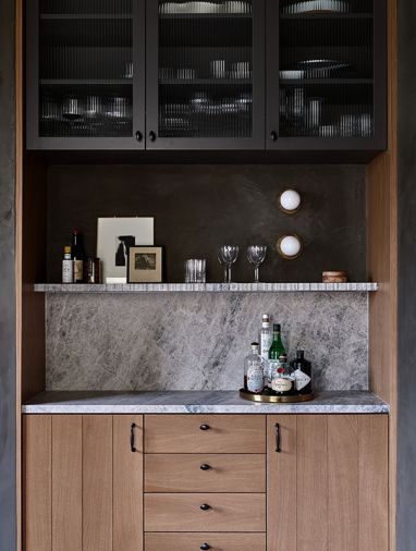 A favorite entertaining detail is the custom-built bar in the dining room. Reeded glass subtly conceals the glassware and bar tools in the upper cabinet. Allure Quartzite shelves and backsplash pull the look together.