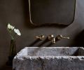 The powder room brings the intentionality of the renovation into a small space. Deep brown plaster walls, natural stone sink from Oda & King, and unlacquered brass Newport fixtures.