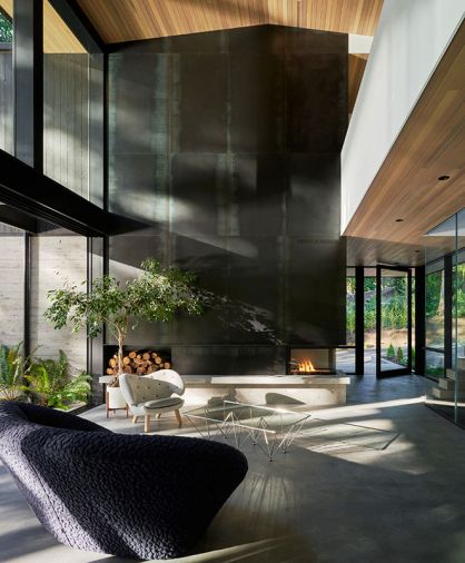 A sculptural fireplace warms the living room with a Fieldworks Custom Concrete hearth. Blackened steel surround craftsmanship by Interbay Wood and Metal. Iconic furnishings include the Noguchi coffee table and Ligne Roset sofa.