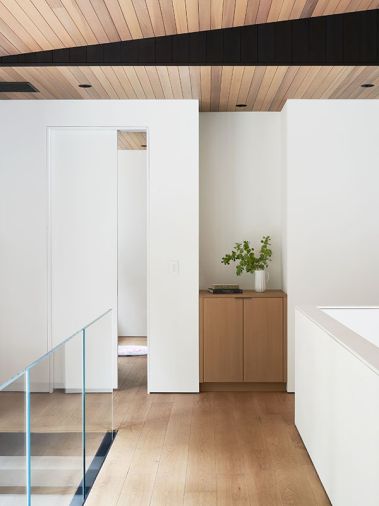 The stairway feels light and airy with a glass surround set against Wixom “New Haven” European oak flooring from Northern Wide Plank. Floor-to-ceiling windows overlook the forested landscape.