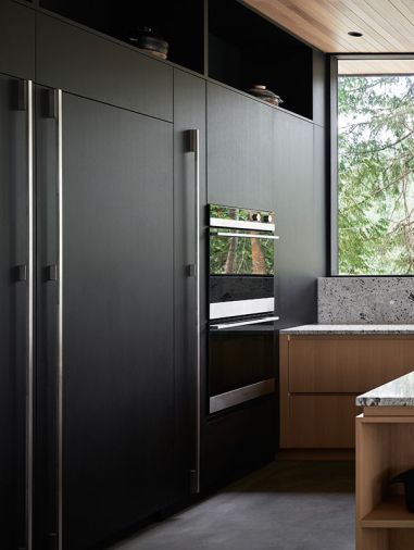 Elegant white oak cabinetry by Interbay Wood and Metal pairs with a custom ebonized stain. Nordic Winter granite counters and slim-profile appliances fade in with a natural look.