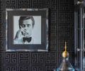 A picture of Sir Roger Moore was placed in a custom hand-painted faux horn frame, on walls covered in sisal in a Greek key pattern from Schumacher.