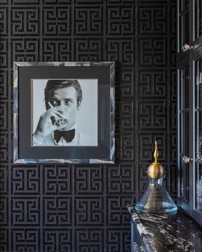 A picture of Sir Roger Moore was placed in a custom hand-painted faux horn frame, on walls covered in sisal in a Greek key pattern from Schumacher.