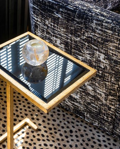 A vintage iron gold leaf table with black glass is a showstopper in the den.