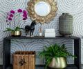 On the stair landing, the walls have Schumacher wallpaper, with a Made Goods console table and a mirror composed of ornate feathers in polished brass from Global Views.