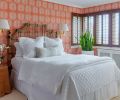 Walls are covered in “Coral Palm Fronds” from Serena & Lily in the guest room. An organic vintage side table and bamboo headboard are balanced with brass swing arm sconces.