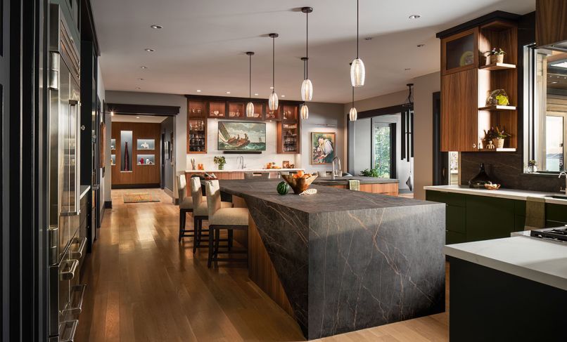 Hand-spun glass thread pendants from Trammell Gagne hang over the large kitchen island, which is wrapped in Cosentino counters fabricated by Progranite Surfaces llc.