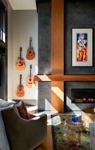 A custom Peacock Rug from Andonian Rugs lies before a fireplace composed of Venetian plaster by Level 5 and quarter-sawn walnut. A Murano glass side table adds elegance in amethyst.