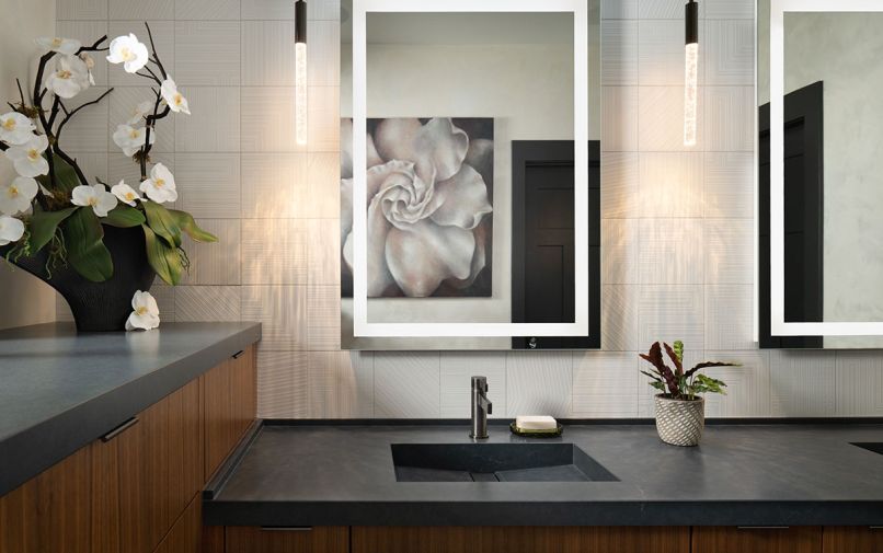 The walls of the primary bathroom are covered in Dal Tile’s Geo Fusion Tile in “Pearl” sourced from Contract Furnishings Mart, and the counters and integrated sink are from Cosentino.