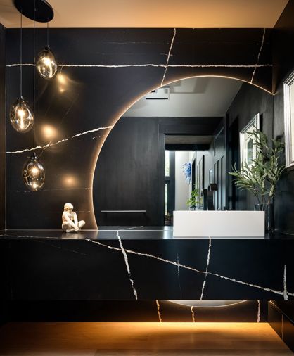 In the powder room, the floating vanity and full-height backsplash in Silestone Et Noir from Cosentino, while the Sonneman Liquid LED Pendants in smoked glass are from Northcoast Lighting.