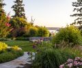 The garden thrives with blooming Crepe Myrtle trees, Moudry Fountain Grass and Jing Yu Tree Peony, which encircle SHD Landscape Architecture’s impressive landscape design. The curved stone wall, built by Johnson Construction, overlooks Lake Washington.