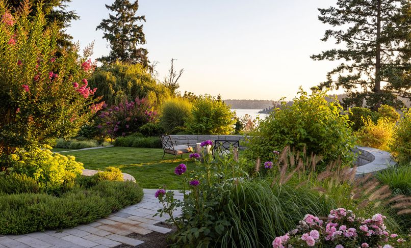 The garden thrives with blooming Crepe Myrtle trees, Moudry Fountain Grass and Jing Yu Tree Peony, which encircle SHD Landscape Architecture’s impressive landscape design. The curved stone wall, built by Johnson Construction, overlooks Lake Washington.