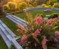Elegant Grey Sandstone steps sourced from Quarry SE, Inc. span transition to lawn below. Baker-McGuire furnishings with Sunbrella cushions overlook Morning Light Maiden Grass and Lily Turf.