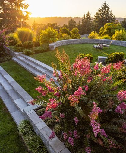 Elegant Grey Sandstone steps sourced from Quarry SE, Inc. span transition to lawn below. Baker-McGuire furnishings with Sunbrella cushions overlook Morning Light Maiden Grass and Lily Turf.