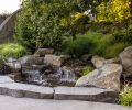 The water feature that abuts the driveway is one of two located adjacent to the south deck. Turnstone Construction utilized Weathered High Cascade Granite to create the peace-making waterfall.