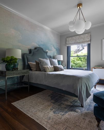 A dreamy bedroom’s Anewall Blue & Grey Cloud wallpaper floats right into a custom Ainsworth bed from Anthropologie. Converted antique trays become a unique bedside table.