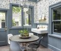 The homeowner enjoys puttering in the restored sunroom with its heated tile floor and farmhouse sink. She chose Anthropologie’s “Fantaisie” wallpaper which pops against Benjamin Moore “Black Pepper” paint.