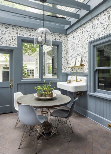 The homeowner enjoys puttering in the restored sunroom with its heated tile floor and farmhouse sink. She chose Anthropologie’s “Fantaisie” wallpaper which pops against Benjamin Moore “Black Pepper” paint.