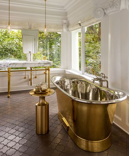 The Brass Bateau nickel interior tub from Catchpole & Rye gleams alongside a pair of solid brass trimmed Gubi wall mirrors that appear to float above the marble console. Arto Arabesque pattern Arto terra cotta tile lines the floor.