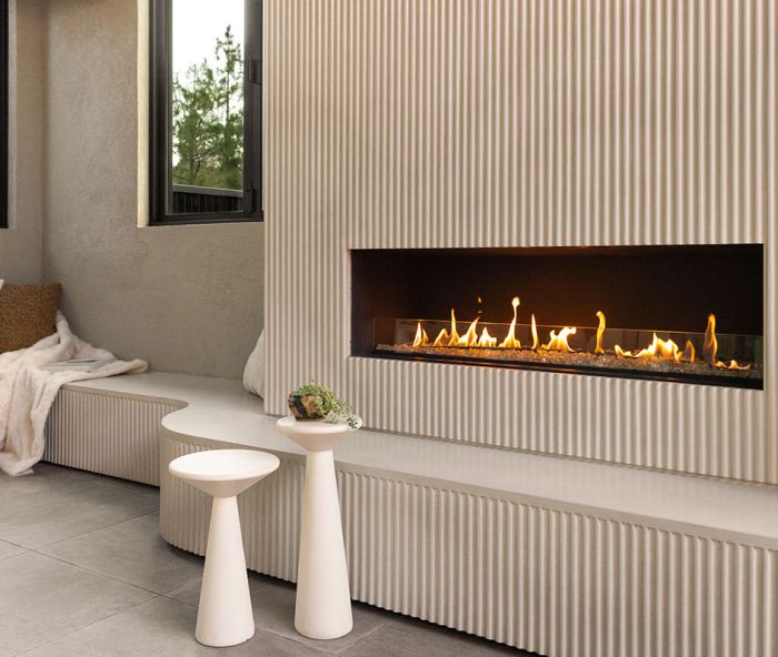 The revamped entertaining area is full of details, including a custom fluted concrete fireplace and curved seating area, a focal point of the space.