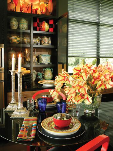 An arrangement of Texas Flame Parrot Tulips brightens the kitchen&rsquo;s cozy dining area with Zarina chairs from Andreau World. An exquisite black ebonized cabinet by L & Z Specialties, Inc. displays cherished collections from travels abroad.