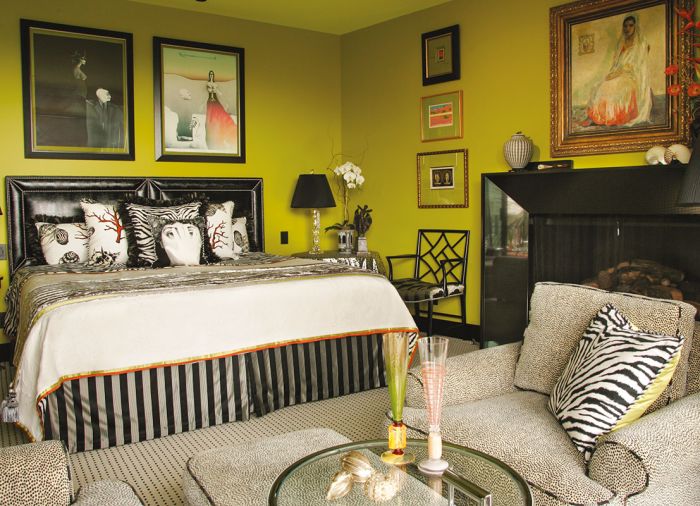 The bed is adorned with platinum faux chinchilla linens. Artwork by Louise Gilbert, Marguerita, graces the fireplace and overlooks a comfy pair of Westcraft chairs reupholstered in Kravet.