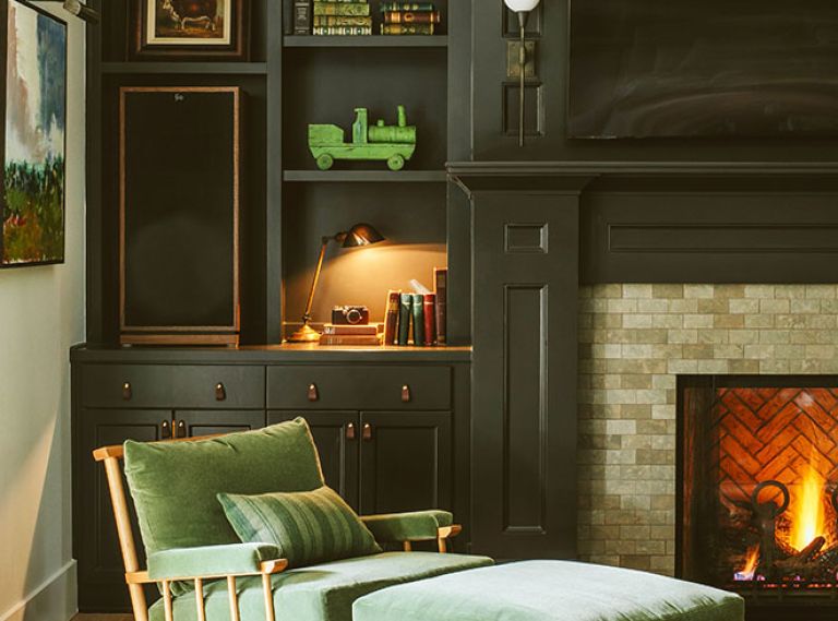 Humphrey obscures the television by painting the adjacent cabinetry in Benjamin Moore &ldquo;Cheating Heart&rdquo;. Mohair cushions on Nickey Kehoe chair play off colors in the rug.