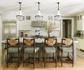 Working within the confines of the existing kitchen design, Humphrey adds panache with an Ann Sacks backsplash. Dramatic pendants reiterate the stainless-steel range hood. With the formal dining room opening to kitchen, the counter stools&rsquo; woven backs echo the dining light fixture.