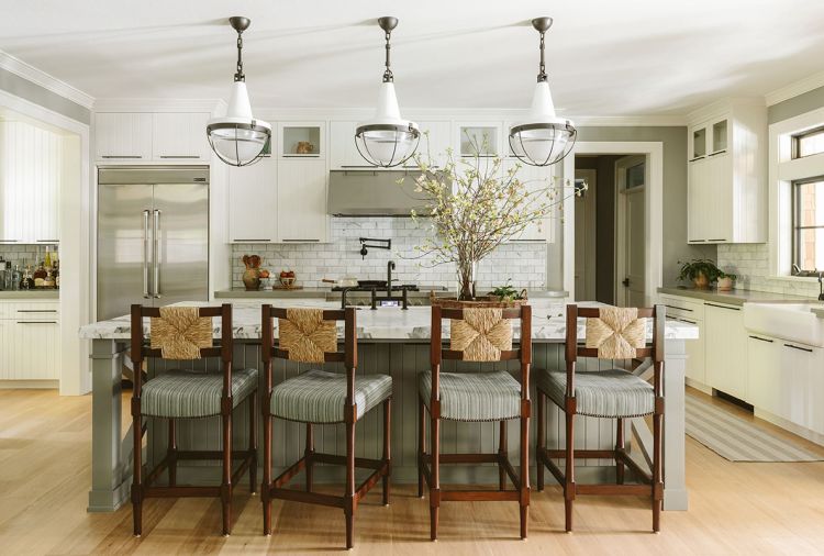 Working within the confines of the existing kitchen design, Humphrey adds panache with an Ann Sacks backsplash. Dramatic pendants reiterate the stainless-steel range hood. With the formal dining room opening to kitchen, the counter stools&rsquo; woven backs echo the dining light fixture.