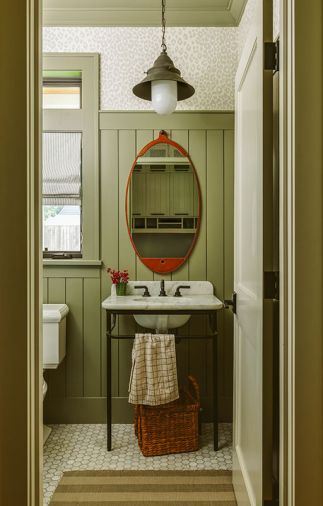 The makeover of the powder room reiterates the home&rsquo;s board and batten wall grounded by an Ann Sacks tile floor. A Rejuvenation vanity and striped window covering from The Shade Store pair with a subtle yet classy leopard print wallcovering.