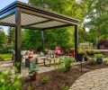 The freestanding louvered pergola in &ldquo;Onyx&rdquo; from The Luxury Pergola adds year-round protection to seating area and firepit which sits on top of Panorama Flag pavers. The lighting along the pathway adds dimension at night.