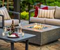 A cozy evening gathering is held around the fire feature as the intimate space glows beneath the pergola. The area adjoins a 3-piece patio wicker bar set from Avawing.