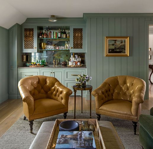 The bar area features two stately custom leather Moore and Giles chairs. Along the wall are excellent accessories and handsome Armac Martin regency metal two-tone metal and glass cupboards for cocktail glass storage. Metallic hardware and plumbing fixtures complete the look.