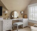A pair of sconces join with natural light for better vanity mirror viewing. The custom stool upholstered in Kerry Joyce Fabric completes the soft and inviting design.