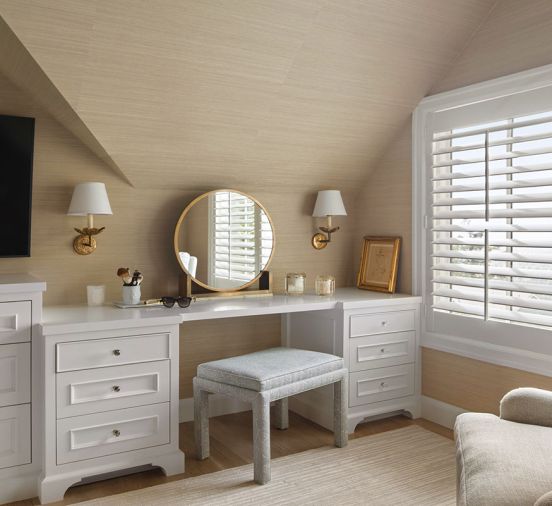 A pair of sconces join with natural light for better vanity mirror viewing. The custom stool upholstered in Kerry Joyce Fabric completes the soft and inviting design.