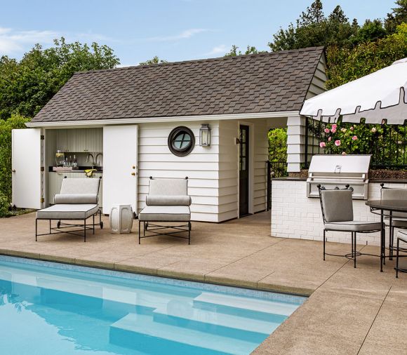 Green Gables&rsquo; new multi-purpose pool house includes a built-in Hestan grill from Eastbank Contractor Appliances. Doors open to protect a versatile wet bar, storage and refrigerator. A dining area and chaise lounges by Amalfi offer a welcoming entertaining space.