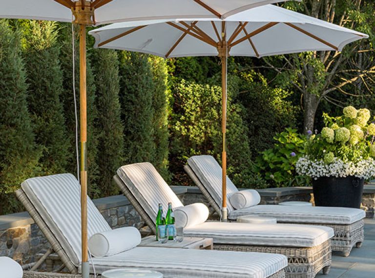 The chic outdoor space has room for lounging and conversation with a series of Kingsley Bate lounges, umbrellas, and ceramic side tables.